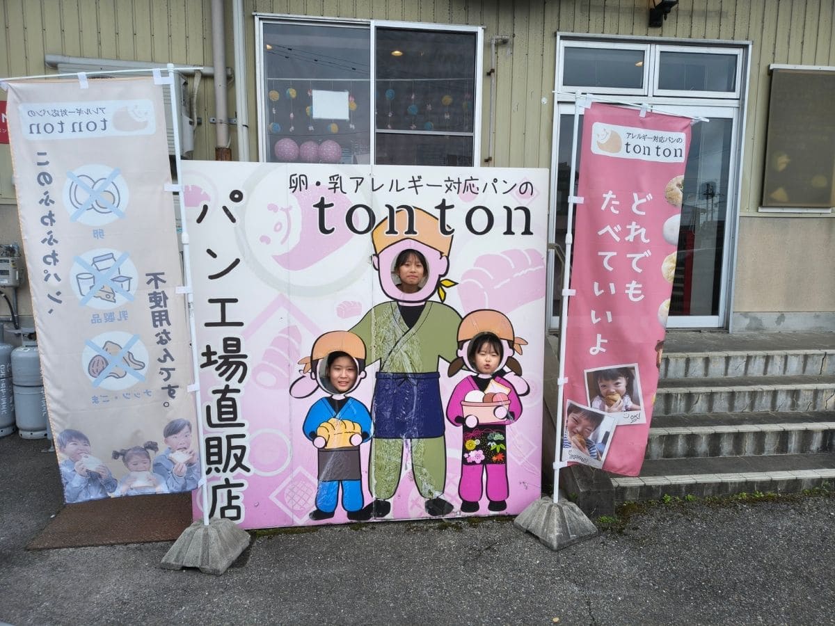 パン工場の直販店の前に立つ、子どもたちの写真が入ったのぼり2本 | アレルギー対応パンのtonton
