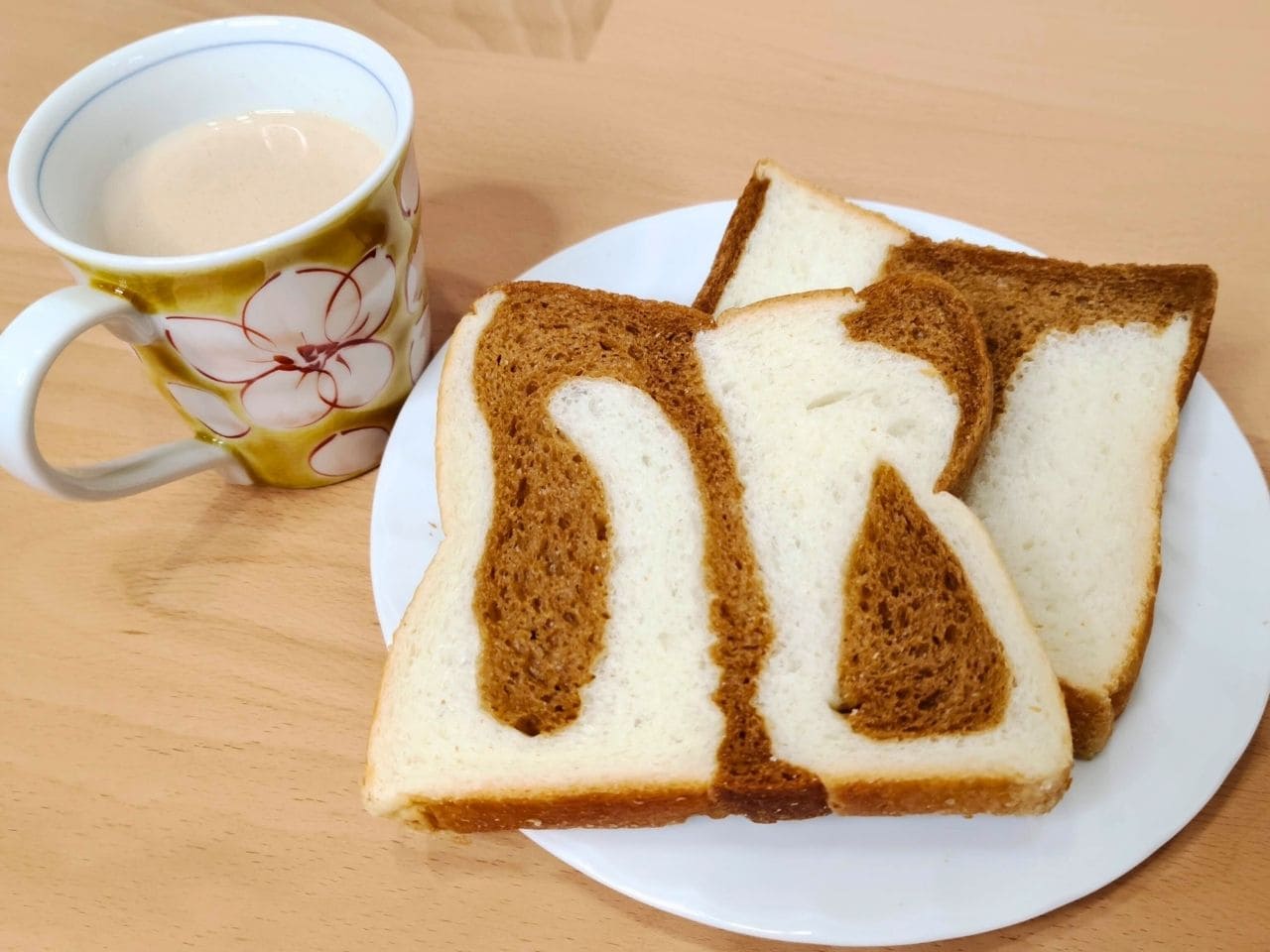 白いお皿にのせたマーブル食パン2枚と、飲み物の入ったマグカップ | アレルギー対応パンのtonton
