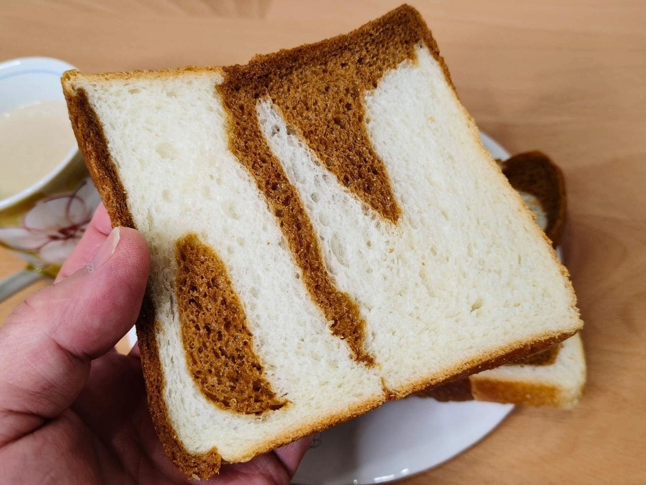 手に持ったマーブル食パン1枚。画像2とは違う模様の断面 | アレルギー対応パンのtonton
